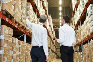Two men in business attire viewing warehouse inventory